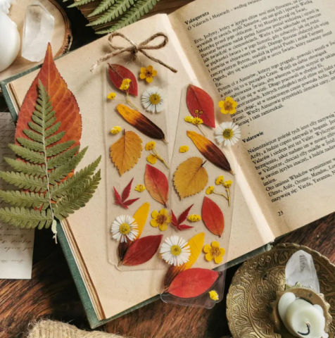 Bookmarks with dried leaves sitting on top of a book.