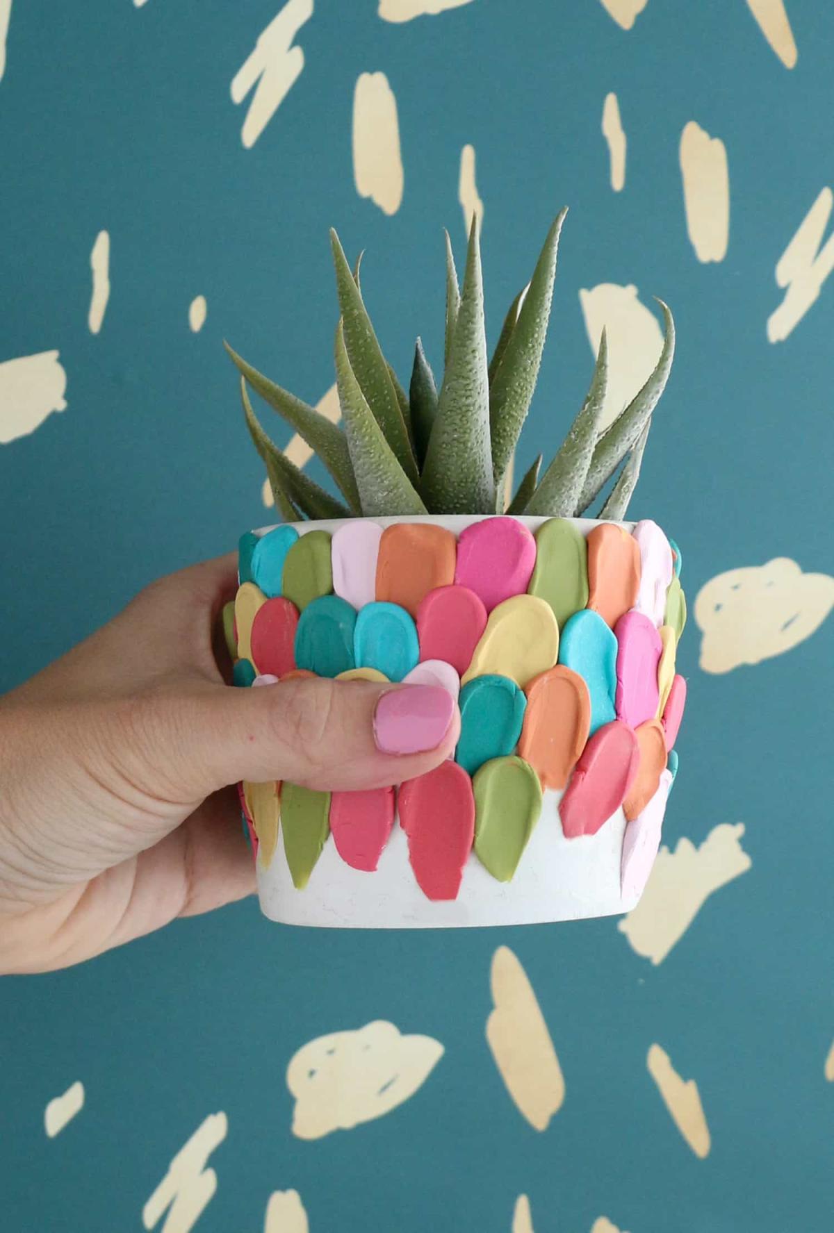 Hand holding a planter decorated with polymer clay